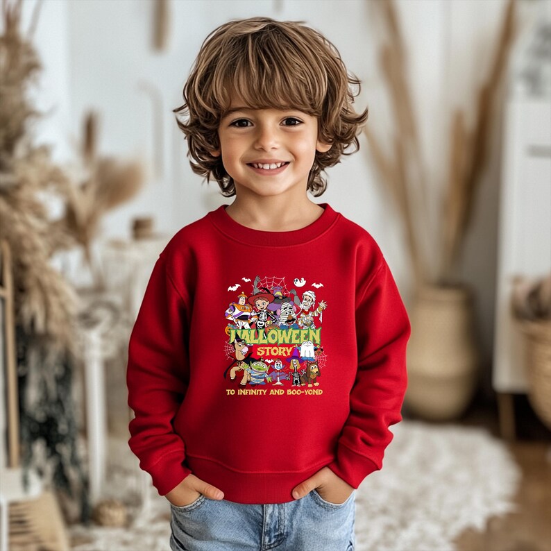 May include: A bright red long-sleeve sweatshirt featuring a colorful graphic print of various cartoon characters in Halloween costumes. The text on the graphic reads "HALLOWEEN STORY" and "TO INFINITY AND BOO-YOND" in bold, stylized lettering.