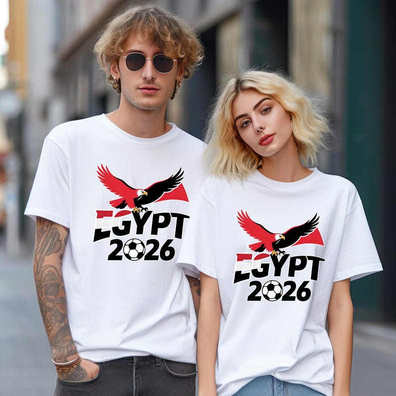 May include: White t-shirts with a graphic design. The design includes a red and black eagle, the word "EGYPT", a football, and the year "2026". The shirts are short-sleeved.