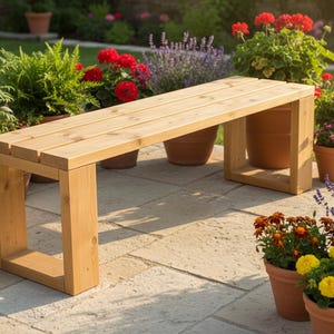 Può includere: Una panca in legno chiaro con seduta rettangolare e gambe quadrate. La panca è circondata da piante in vaso con fiori rossi, gialli e viola. La scena è ambientata all'aperto su un patio in pietra.