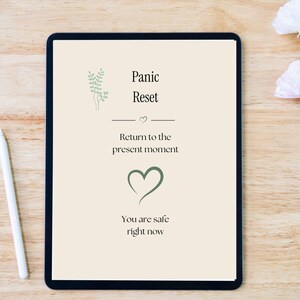 May include: A digital tablet displaying a cream-colored screen with the text Panic Reset, Return to the present moment, and You are safe right now, accompanied by a green leaf illustration and a heart icon, next to a white stylus.