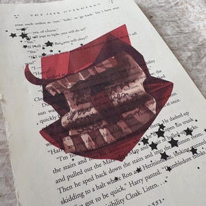 May include: A page from a book titled The Seer Overheard, featuring printed black text and a central red graphic illustration of a hat. The page is decorated with small black star icons scattered across the text and the illustration.