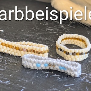 Könnte beinhalten: Nahaufnahme von drei Perlenringen. Die Ringe sind in Weiß-, Gold- und Grautönen gehalten, mit dem Text "Farbbeispiele" oben. Die Ringe werden auf einer dunklen Oberfläche präsentiert.