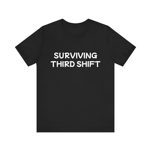 May include: Black crew neck t-shirt with the white text "SURVIVING THIRD SHIFT" printed across the chest. The short-sleeved shirt is made of a soft material and is suitable for casual wear.