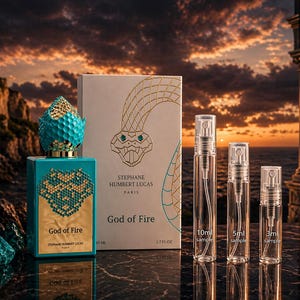 以下が含まれることがあります： 金とターコイズの模様、金色のキャップ、そして「God of Fire」の文字が入ったターコイズの香水瓶。その隣には、ヘビのイラストと「God of Fire」の文字が入った箱があります。10ml、5ml、3mlとラベルされた3つのサンプルスプレーボトルも表示されています。