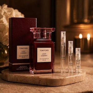 May include: A Tom Ford "Lost Cherry" Eau de Parfum set. The set includes a burgundy-colored perfume bottle, a matching box, and three sample spray bottles. The perfume bottle has a rectangular shape with a crystal-like cap.