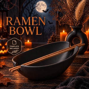 Könnte beinhalten: Eine mattschwarze Keramik-Ramenschale mit zwei integrierten Einkerbungen am Rand zum Ablegen eines Paares hellbrauner Holzstäbchen. Die Schale zeigt den Text RAMEN BOWL und ein Abzeichen mit der Aufschrift TEMPLATE INCLUDED in dunkler Umgebung.