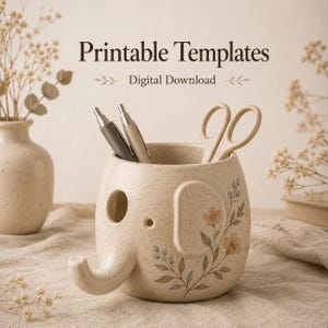 Könnte beinhalten: Ein gesprenkelter, beigefarbener Schreibtisch-Organizer aus Keramik in Elefantenform mit einem Blumenmuster an der Seite. Der Text 'Printable Templates' und 'Digital Download' steht darüber. Zwei Stifte und eine Schere stecken darin.