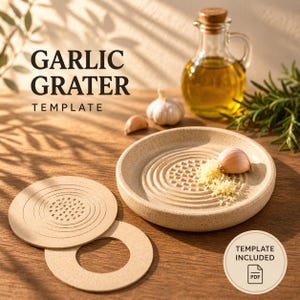 Peut inclure: Un presse-ail en céramique beige avec une gousse d'ail et de l'ail râpé. L'image montre également une petite bouteille d'huile en verre, une tête d'ail entière et deux gabarits ronds. Le texte sur l'image indique "GARLIC GRATER TEMPLATE".