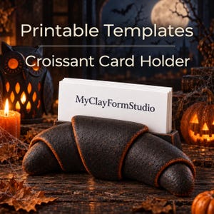 以下が含まれることがあります： MyClayFormStudioと印刷された白い名刺の束を保持する、黒いクロワッサン型のカードホルダー。カードホルダーの上部には、白いフォントでPrintable Templates Croissant Card Holderというテキストが表示されています。