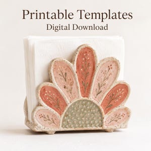 May include: A ceramic napkin holder shaped like a flower with speckled pink and sage green petals, each featuring hand-painted botanical sprigs. The holder contains a stack of white paper napkins. Text above reads Printable Templates Digital Download.