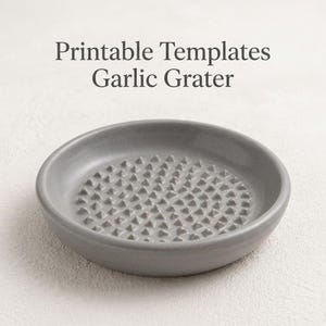 Könnte beinhalten: Ein grauer Knoblauchreibe aus Keramik mit strukturierter Oberfläche. Die Reibe ist rund mit einer flachen Schalenform und trägt die Aufschrift "Printable Templates Garlic Grater". Die Oberfläche ist mit kleinen, erhabenen, dreieckigen Formen bedeckt.