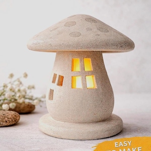 Op de afbeelding: Een beige paddenstoelvormig huis met een gestippelde kap en rechthoekige ramen die oplichten met een oranje licht. De tekst "Mushroom House" staat bovenaan. De woorden "Easy to Make" en "Digital Download" zijn ook zichtbaar.