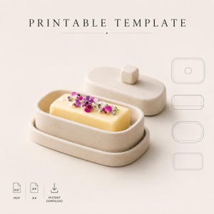Può includere: Un portasapone beige con una saponetta rettangolare decorata con fiori viola e bianchi. Il coperchio è rimosso e le parole "PRINTABLE TEMPLATE" sono in alto. Ci sono anche icone PDF e A4 e un'icona di download immediato.
