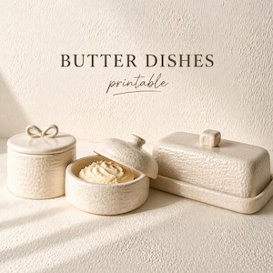 May include: Cream-colored ceramic butter dishes. One round dish with a bow-shaped handle, a small round dish with butter inside, and a rectangular butter dish with a square handle. The text "BUTTER DISHES printable" is at the top.