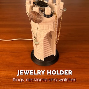May include: A light pink jewelry holder shaped like a castle tower, with a black base. The tower holds a watch, rings, and necklaces. The text "JEWELRY HOLDER" and "Rings, necklaces and watches" are visible.