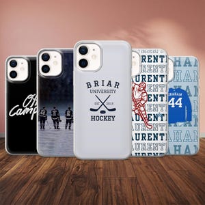 May include: A collection of phone cases with various designs. One case has the text "Off Camp" in white on a black background. Another features hockey players. Other cases display "Briar University Hockey" and a hockey player graphic. One case has the name "Graham 44".