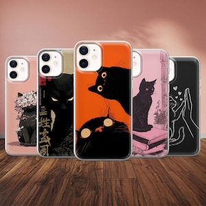 May include: A collection of five phone cases with unique cat-themed designs. The cases feature illustrations of black cats in various poses and settings, including floral accents and Japanese-inspired art. The cases are displayed on a wooden surface.