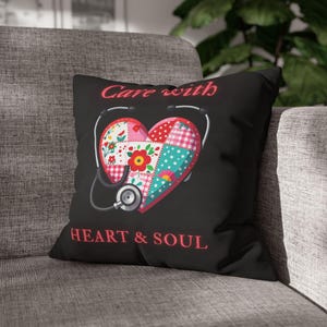May include: A black square throw pillow featuring a central heart graphic composed of various colorful floral and checkered quilt-like patterns. A silver stethoscope frames the heart. The text "Care with" and "HEART & SOUL" is printed in red.