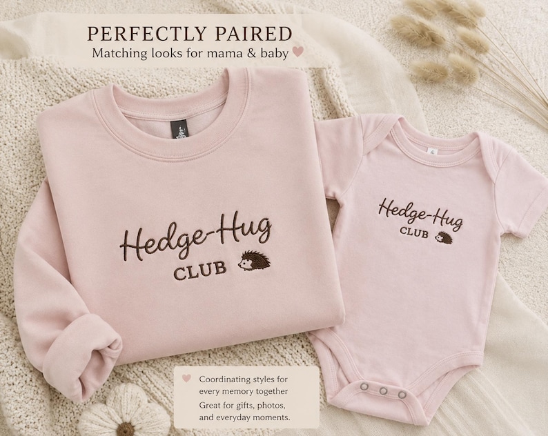 May include: A light pink long-sleeve sweatshirt and a matching short-sleeve baby bodysuit. Both garments feature dark brown embroidered text that reads Hedge-Hug CLUB with a small hedgehog graphic. The set is designed for coordinated outfits.