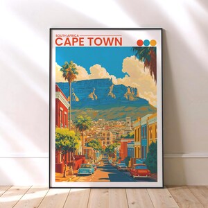 Può includere: Una stampa artistica incorniciata con un'illustrazione colorata di Città del Capo, Sudafrica. L'opera raffigura una scena stradale con palme, edifici e una montagna sullo sfondo. Il testo "SOUTH AFRICA - CAPE TOWN" è in alto.
