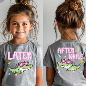 May include: Athletic heather gray t-shirt with a cartoon alligator wearing pink sunglasses. The front of the shirt says "LATER" in pink letters. The back of the shirt says "AFTER WHILE" in pink letters.