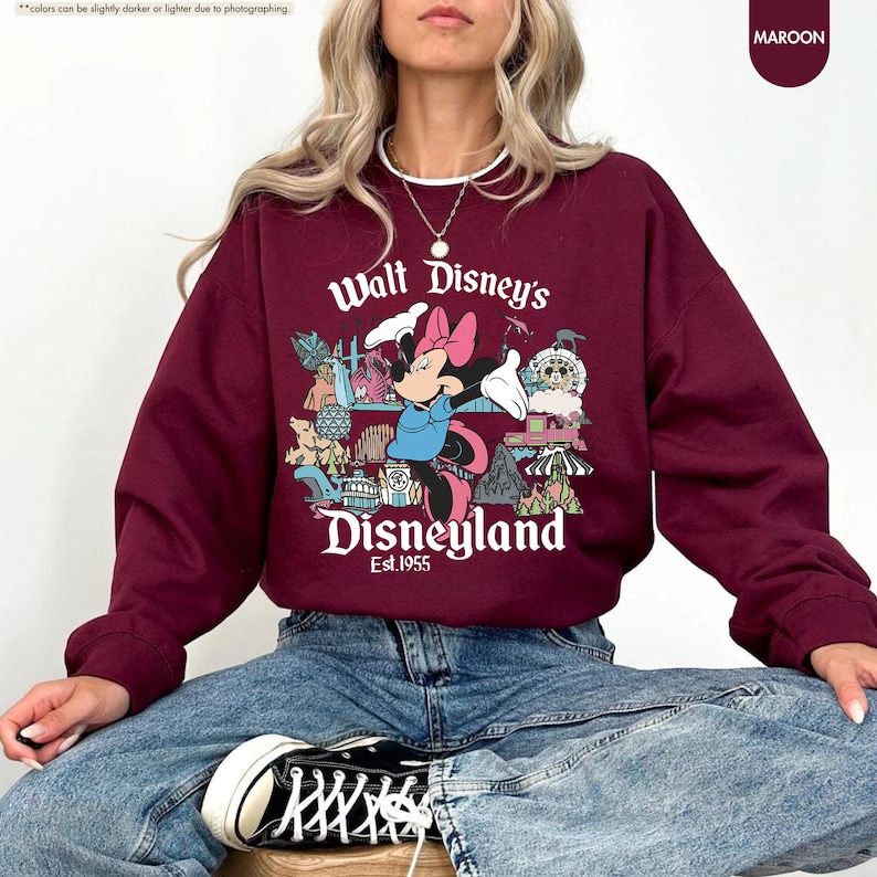 Pu&ograve; includere: Felpa bordeaux con grafica di Minnie Mouse e la scritta "Walt Disney's Disneyland Est.1955". Il design include varie icone del parco Disney. La felpa &egrave; di colore bordeaux unito.