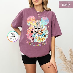 K&ouml;nnte beinhalten: Beerenfarbenes T-Shirt mit einem farbenfrohen Aufdruck von Mickey Mouse, Minnie Mouse, Donald Duck, Goofy und Pluto vor einem Schloss. Der Text "Magic Summer 2026" ist darunter aufgedruckt. Das Shirt hat eine lockere Passform.
