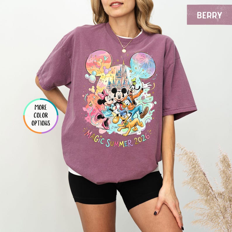 K&ouml;nnte beinhalten: Beerenfarbenes T-Shirt mit einem farbenfrohen Aufdruck von Mickey Mouse, Minnie Mouse, Donald Duck, Goofy und Pluto vor einem Schloss. Der Text "Magic Summer 2026" ist darunter aufgedruckt. Das Shirt hat eine lockere Passform.