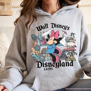 Pu&ograve; includere: Felpa grigio sportiva con Minnie Mouse e la scritta "Walt Disney's Disneyland Est.1955". Il design include varie attrazioni di Disneyland. La felpa ha una tasca frontale e un cappuccio con coulisse.