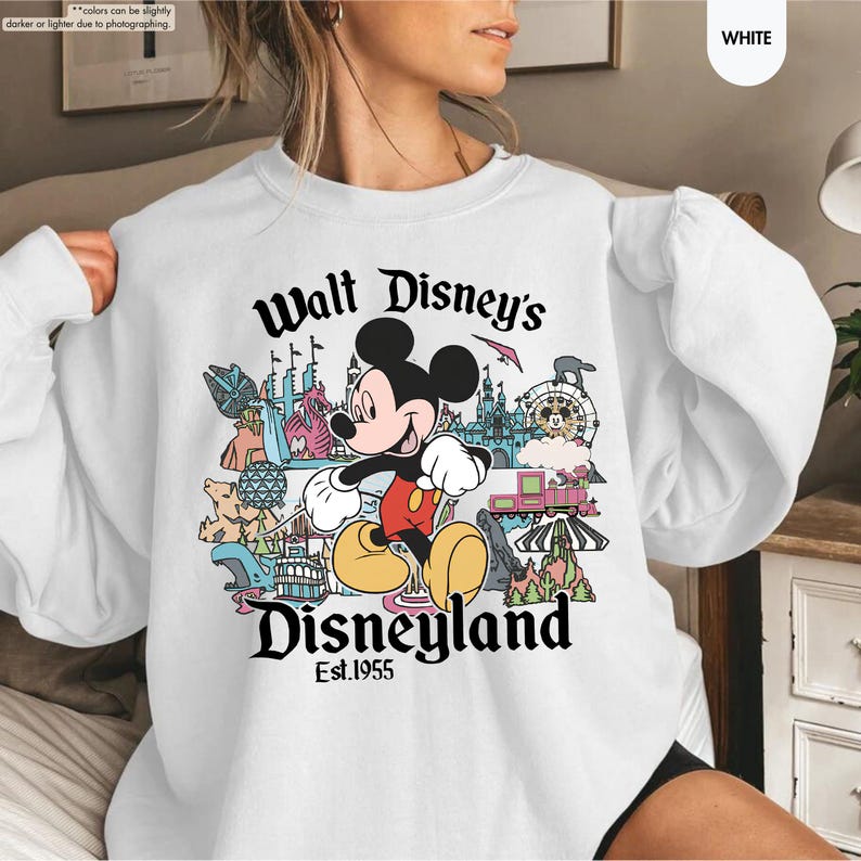 Pu&ograve; includere: Felpa bianca con una grafica colorata di Topolino e delle attrazioni di Disneyland. Il testo "Walt Disney's Disneyland Est.1955" &egrave; stampato in nero. La felpa &egrave; a girocollo.