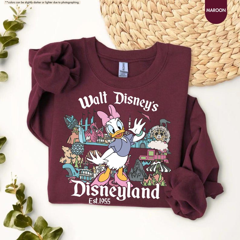 Pu&ograve; includere: Felpa bordeaux con una grafica di Paperina davanti alle attrazioni di Disneyland. Il testo "Walt Disney's Disneyland Est.1955" &egrave; stampato in bianco. La felpa &egrave; realizzata in materiale morbido e ha maniche lunghe.