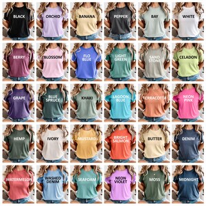 May include: A collection of crew neck t-shirts in various colors, each labeled with its color name in white capital letters. Colors include black, orchid, banana, pepper, bay, white, berry, blossom, flo blue, light green, sand stone, celadon, grape, blue spruce, khaki, lagoon blue, terracotta, neon pink, hemp, ivory, mustard, bright salmon, butter, denim, watermelon, washed denim, seafoam, neon violet, moss, and midnight.