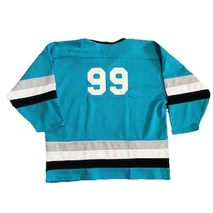May include: A turquoise hockey jersey with the number 99 in white on the back. The jersey has black, white, and gray stripes on the sleeves and bottom hem. The jersey is made of a mesh material.