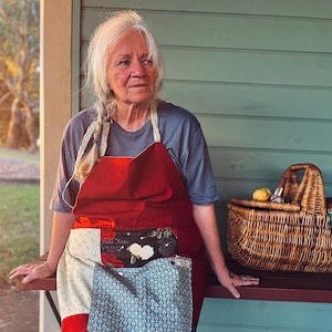 May include: A white ceramic mug with a black handle and the text "But First, Coffee" in a bold, black font. The mug is filled with a dark liquid, probably coffee, and rests on a light-coloured surface.
