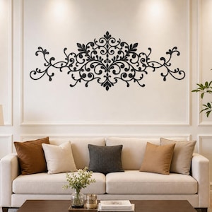 May include: A black wall-mounted decorative piece featuring an intricate, symmetrical scrollwork design with swirling patterns and leaf-like motifs. The object is horizontally oriented and displays a complex, interconnected filigree structure.