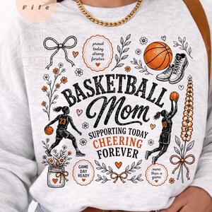 Puede incluir: Una sudadera gris claro con un dise&ntilde;o tem&aacute;tico de baloncesto. El dise&ntilde;o incluye las palabras "BASKETBALL Mom" y "SUPPORTING TODAY CHEERING FOREVER". El dise&ntilde;o tambi&eacute;n presenta balones de baloncesto, una zapatilla de baloncesto y elementos florales.