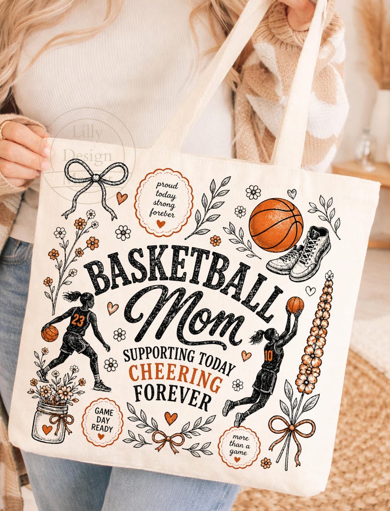 Puede incluir: Bolso tote de color crema con tem&aacute;tica de baloncesto. El dise&ntilde;o incluye las palabras "Basketball Mom" y "Supporting Today Cheering Forever". Presenta ilustraciones de una pelota de baloncesto, una zapatilla de ca&ntilde;a alta y jugadores de baloncesto. Acentos florales y de coraz&oacute;n completan el dise&ntilde;o.