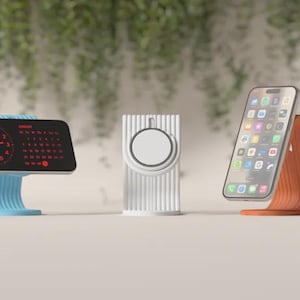 May include: Three modern tech accessories: a blue clock with a red display, a white and silver watch charger, and an orange phone stand. The clock shows a clock face and calendar. The phone displays app icons.