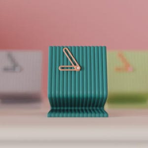 Peut inclure: Plusieurs horloges de bureau modernes et colorées. Les horloges ont un design côtelé et sont disponibles en différentes couleurs, dont le vert d'eau, le rouge et le noir. Chaque horloge présente un cadran minimaliste avec des aiguilles simples.