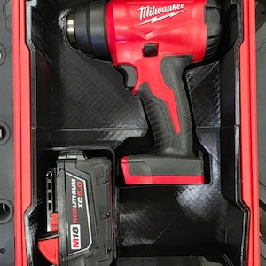 May include: A red and black Milwaukee heat gun and an M18 Redlithium XC5.0 battery stored inside a custom-fitted black insert within a red hard-shell carrying case. The heat gun features a trigger and the Milwaukee logo on the side.