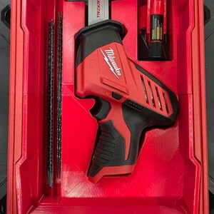 Può includere: Una sega a gattuccio Milwaukee M12 Hackzall rossa e nera con batteria e due lame riposte in una custodia in plastica rossa sagomata. L'utensile presenta il logo Milwaukee e il marchio M12 sul lato dell'alloggiamento.