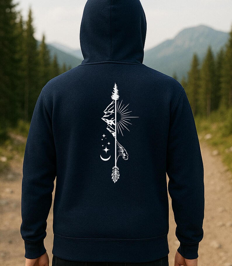 May include: Navy blue hoodie with a white graphic on the back featuring a mountain range, sun, arrow, and stars. The hoodie has a hood and a drawstring. The background shows a forest and a mountain range.