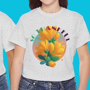 May include: Two light grey t-shirts with a floral design and the words "SO THANKFUL" in a circular pattern. The floral design features yellow flowers with green leaves. The models are wearing blue jeans.