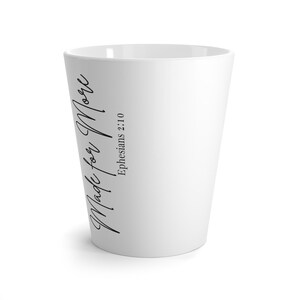 Op de afbeelding: Witte keramische mok met een taps toelopend ontwerp. De mok heeft de tekst "Made for More" in een stijlvol schrift, samen met de verwijzing "Efeziërs 2:10". Geschikt voor warme of koude dranken.