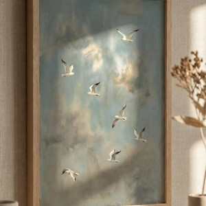 May include: A framed artwork featuring a flock of seagulls in flight against a cloudy sky. The painting has a soft, muted color palette of blues, whites, and browns. The wooden frame adds a natural touch to the artwork.