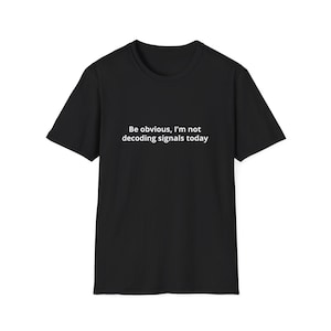 Puede incluir: Camiseta negra con el texto blanco: "Be obvious, I'm not decoding signals today." La camiseta de manga corta está hecha de un material suave y es adecuada para ropa informal. El texto está centrado en la parte delantera de la camiseta.
