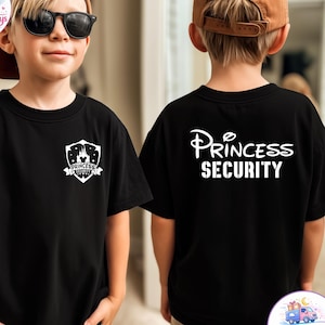 May include: Black t-shirt with a white graphic on the front and back. The front graphic is a shield with a castle and the words "Princess Security". The back of the shirt has the words "Princess Security" in a script font.