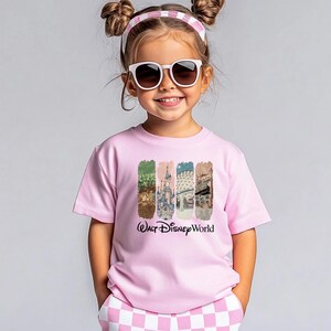 Puede incluir: Una camiseta rosa con un gr&aacute;fico de "Walt Disney World". El gr&aacute;fico presenta cuatro im&aacute;genes rectangulares verticales con escenas de parques de Disney. La ni&ntilde;a lleva gafas de sol y una diadema rosa y blanca.
