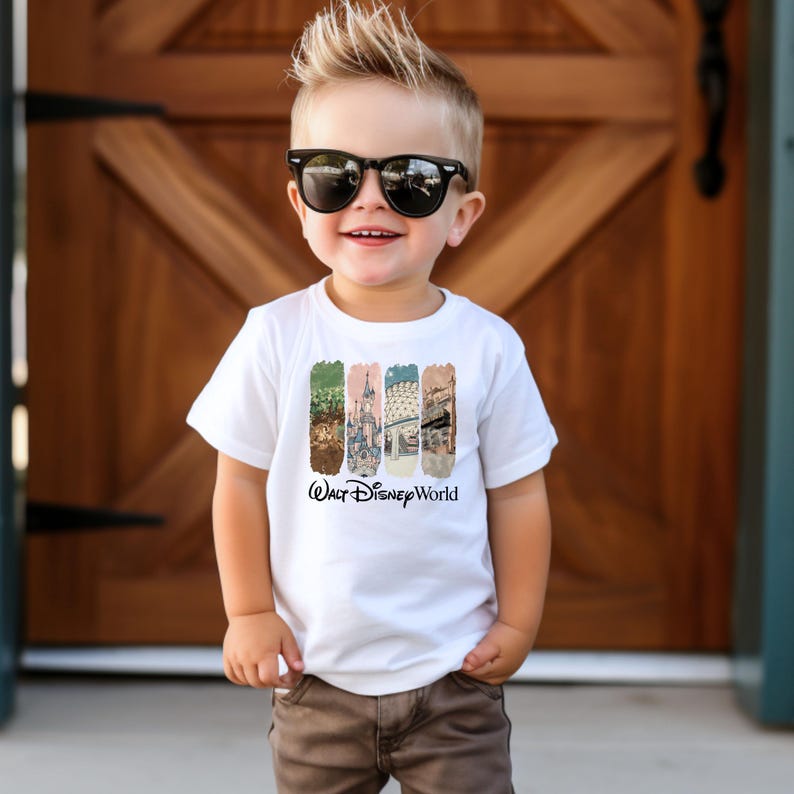 Puede incluir: Camiseta blanca con un gr&aacute;fico colorido con im&aacute;genes de Walt Disney World. La camiseta tiene las palabras "Walt Disney World" impresas en negro. El ni&ntilde;o lleva gafas de sol y pantalones marrones.
