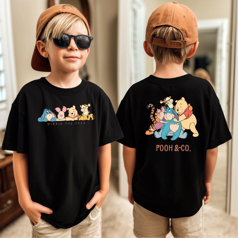 May include: Black t-shirt featuring Winnie the Pooh characters on the front and back. The front displays Eeyore, Piglet, Winnie the Pooh, and Tigger with the text "WINNIE THE POOH". The back shows the characters with the text "POOH & CO."